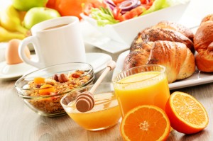 A breakfast of coffee, bread, honey, orange juice, muesli and fruits