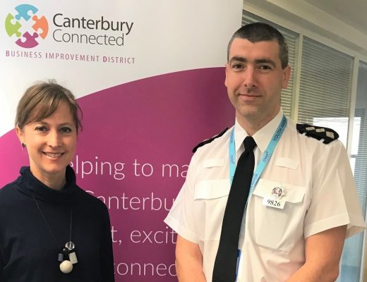 A man and a woman, Lisa and Mark, posing for a photo in front of a Canterbury BID event banner