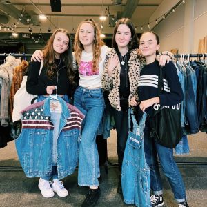 A photo of four girls posing for a photo in a shop