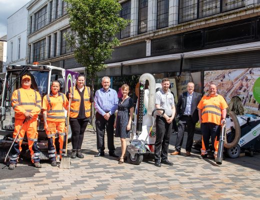 A group photo of some people in a high street with public cleaning equipment